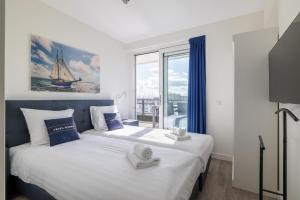a bedroom with two beds and a large window at Vakantiewoning aan het water - met 2 balkons - Vista Maris - Nr 52 in Sint Annaland