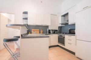kuchnia z białymi szafkami i stołkiem barowym w obiekcie Spacious 2-bedroom in the centre of Menton w Mentonie