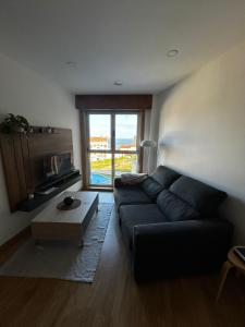 a living room with a black couch and a large window at Malpica Beach in Malpica
