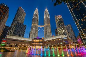 a fountain in front of the petronas towers at night at Apartment Sky by MonoSuites KLCC in Kuala Lumpur