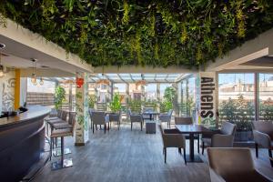 a restaurant with tables and chairs and plants on the ceiling at Athens Way Pop Art Hotel in Athens