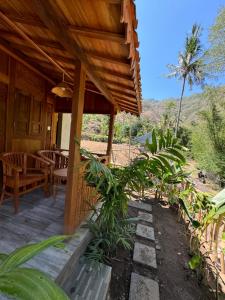 a porch of a house with a table and chairs at Oemah Kangin Homestay in Amed