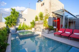 a swimming pool with red chairs next to a house at Palo Santo Hotel in Buenos Aires