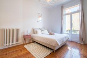 biała sypialnia z łóżkiem i oknem w obiekcie Spacious 2-bedroom in the centre of Menton w Mentonie