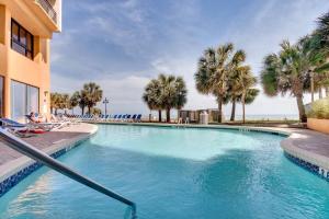 默特尔比奇Captivating Coastal Charm - Oceanview Suite! PG 504的有棕榈树的游泳池和一栋建筑