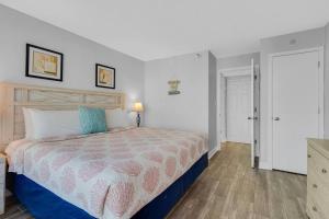 默特尔比奇Captivating Coastal Charm - Oceanview Suite! PG 504的卧室里有一张床，床铺有蓝白相间的被子 更多22张照片
