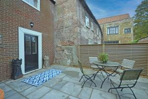 a patio with a table and chairs and a fence at TudorRose Townhouse - A New Unique Town Centre Home in King's Lynn