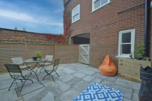 a patio with a table and chairs next to a brick building at TudorRose Townhouse - A New Unique Town Centre Home in King's Lynn +6 photos