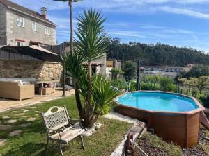 a pool in a yard with a bench and a palm tree at El almacén de Lola Relax, piscina y Vistas al Mar in Pontevedra