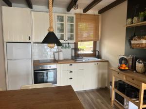 a kitchen with white cabinets and a wooden table at El almacén de Lola Relax, piscina y Vistas al Mar in Pontevedra