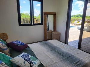 a bedroom with a bed with a view of a deck at SALTY LODGE Villa 3 chambres piscine "ALIZES" - Pointe Faula in Le Vauclin +11 photos