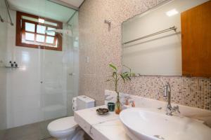 a bathroom with a sink and a toilet and a mirror at Villa Rica Pousada in Brumadinho