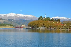 a boat on a lake with mountains in the background at Cozyio- Ioannina City Center, Luxury Accommodation in Ioannina