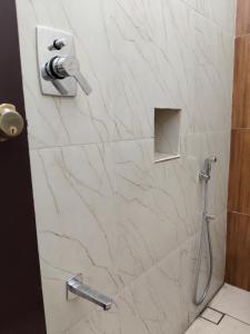 a bathroom with a shower with white marble tiles at SriKrishna Paradise in Tiruvannāmalai