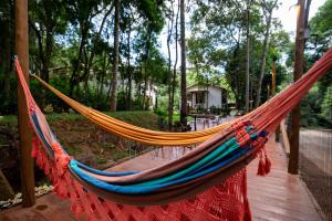 a hammock on a wooden deck with trees at Villa Rica Pousada in Brumadinho