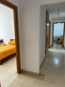 a bedroom with a bed and a hallway with a table at Appart Meublé Cité ElWahat in El Aouina
