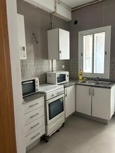 a kitchen with white appliances and a sink at Appart Meublé Cité ElWahat in El Aouina