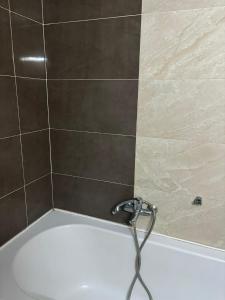 a bath tub with a hose attached to a tile wall at Appart Meublé Cité ElWahat in El Aouina