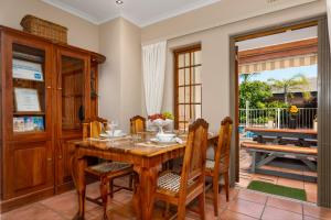 una sala da pranzo con tavolo e sedie in legno di Meerendal Cottage-Affordable Luxury-Private Garden with Pool & Hot Tub a Città del Capo