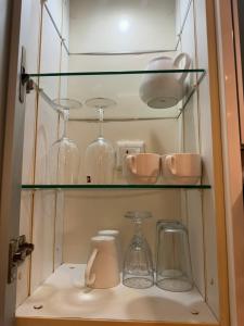 a shelf with glasses and other glass items on it at Sweet Cozy Marina Suite at Straits Quay in Tanjong Tokong +13 photos