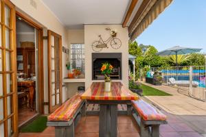 un tavolo e una panca su un patio con camino di Meerendal Cottage-Affordable Luxury-Private Garden with Pool & Hot Tub a Città del Capo