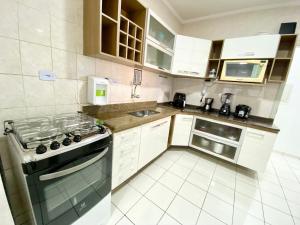 Una pequeña cocina con estufa y fregadero. en Edifício Saint Domingos, en Samaritá 4 fotos más