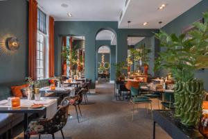 a restaurant with tables and chairs and plants at Van Der Valk Hotel Brugge Oostkamp in Oostkamp