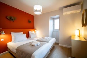 Dos camas en una habitación con una pared naranja. en Le Savane - Grand Triplex Confort & Chaleureux, 2 Salons, en Castres