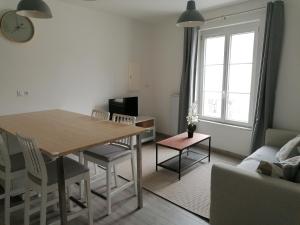 a living room with a table and a couch at Chamaillard 1, calme, draps fournis in L'Ile-Bouchard