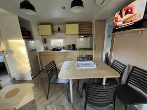 a small kitchen with a table and chairs in a caravan at mobilhome 4 étoiles in Gastes