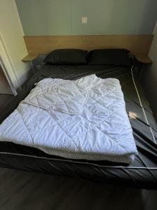 a bed with a white blanket on top of it at mobilhome 4 étoiles in Gastes