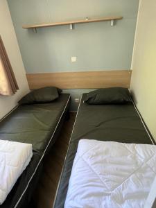 two beds in a small room withacers at mobilhome 4 étoiles in Gastes