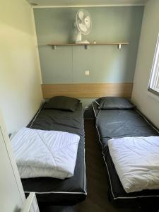 two beds in a small room with a fan at mobilhome 4 étoiles in Gastes