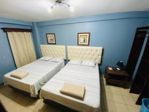 zwei Betten in einem Zimmer mit blauen Wänden in der Unterkunft Merendon Suite Apartamento in San Pedro Sula