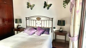 a bedroom with a bed with purple pillows and butterflies on the wall at Villa Lujo y Relax in Adeje by Deihu Experiences in Adeje +34 photos