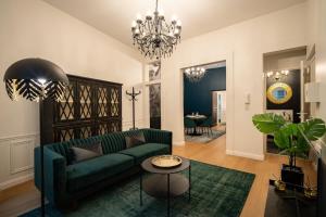 ein Wohnzimmer mit einem grünen Sofa und einem Kronleuchter in der Unterkunft Le Baroque - Grand T2 Confort, Lit Queen Size in Castres + 18 Fotos