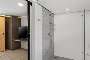 a shower with a glass door and a television at Beach Walk Condo 3br in Replay in Bang Rak Beach