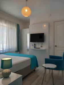 a bedroom with a bed and a tv and a chair at Daffne Pansiyon in Çanakkale