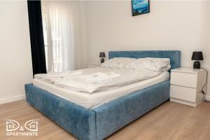 a bed in a room with a blue bed frame at Pine Tree House 9 D&D Apartments in Międzywodzie