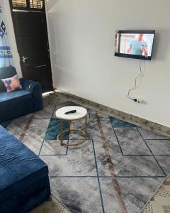 a living room with a table and a tv on a wall at Vanessa villa in Malindi