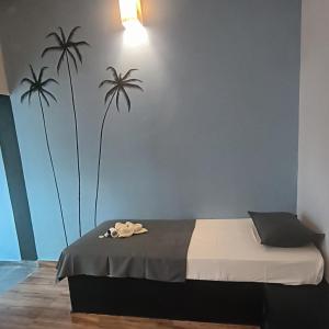 a bedroom with a bed with two palm trees on the wall at Mad about Coco Yoga & Beach Retreat in Varkala