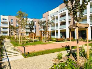 een appartementengebouw met een park ervoor bij DOMITYS - Le Bouquet in Charnay-lès-Mâcon