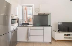 a kitchen with white cabinets and a stainless steel refrigerator at Apartamento con vistas a la playa in Santander