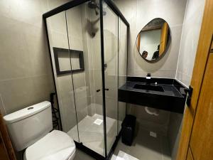 a bathroom with a toilet and a sink and a mirror at Suítes Viver Arraial do Cabo in Arraial do Cabo