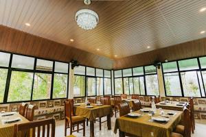 a dining room with tables and chairs and windows at Swag Vista Resort in Anachal