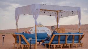 a woman sitting under a tent in the desert at Infinity Camp in Bidiyah