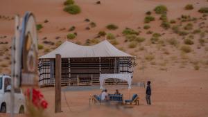 two people sitting under a tent in the desert at Infinity Camp in Bidiyah