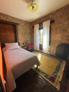 ein Schlafzimmer mit einem Bett und einer Steinwand in der Unterkunft Casona histórica del S XVII en Novales in Novales