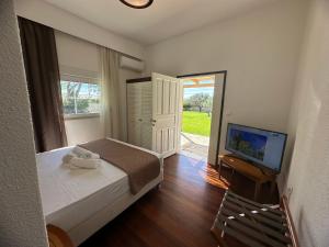 a bedroom with a bed and a television and a door at Villa Komorebi, the Private 3BR Grand Estate - 2500m2 Garden - Walk to Beach & Town in Ierapetra