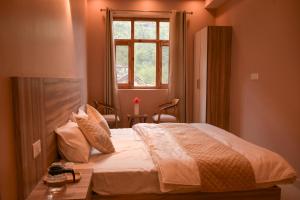 a bedroom with a large bed with a window at Zankhrpas A Himalayan Home - Manali in Manāli